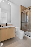 Contemporary bathroom featuring a floating wood-finish vanity with a light-toned countertop and black fixtures - 