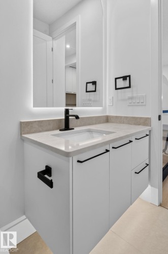 Modern vanity featuring an integrated sink, light-toned countertop, and matte black fixtures - 8791 Mayday Ln Sw Sw, Edmonton, AB - Indoor