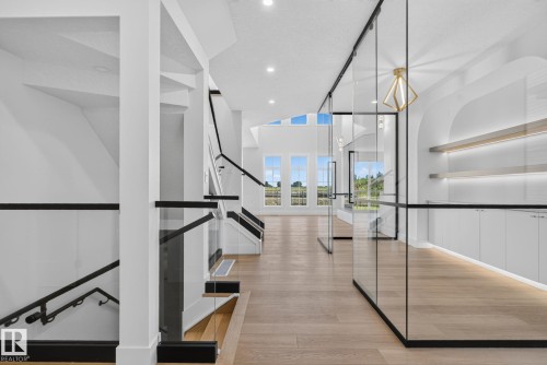 Modern interior featuring light wood-finish flooring and a contemporary staircase with glass railings and dark banisters - 8791 Mayday Ln Sw Sw, Edmonton, AB - Indoor Photo Showing Other Room