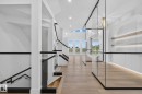 Modern interior featuring light wood-finish flooring and a contemporary staircase with glass railings and dark banisters - 8791 Mayday Ln Sw Sw, Edmonton, AB  - Indoor Photo Showing Other Room 