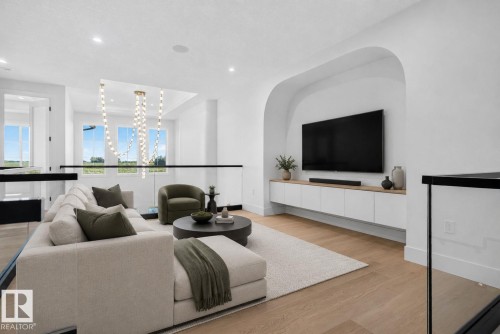 Upper-level living space featuring hardwood-finish flooring and a built-in entertainment unit within an arched wall niche - 8791 Mayday Ln Sw Sw, Edmonton, AB - Indoor Photo Showing Living Room
