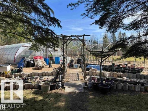 Expansive outdoor area featuring a large greenhouse structure and an adjacent shed - 210 55504 Nikoodi Road, Rural Lac Ste. Anne County, AB - Outdoor