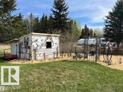 Landscaped outdoor area featuring a decorative shed, mature trees, and a visible greenhouse structure - 