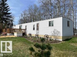 White siding exterior with a wood deck, mature trees, and a garden area - 