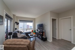 Spacious living area featuring light gray walls and wood-finish flooring - 