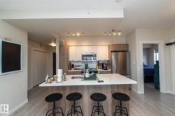 Modern kitchen featuring an island with seating, stainless steel appliances, contemporary cabinetry, a built-in microwave, and track lighting - 