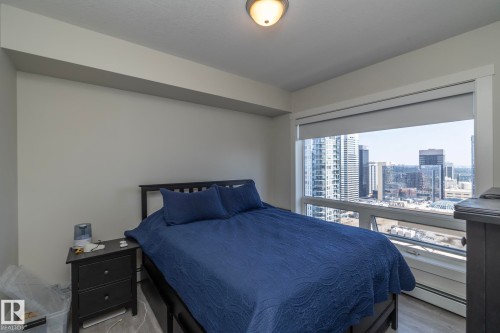Expansive window offering urban scenery, light-colored walls, wood-finish flooring, and a flush mount ceiling light fixture - #2402 10410 102 Av Nw, Edmonton, AB - Indoor Photo Showing Bedroom