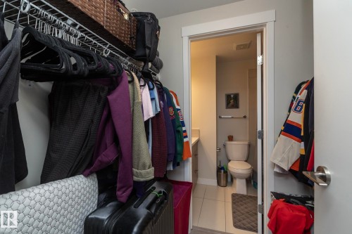 Walk-in closet featuring wire shelving, a full-height hanging rod, and a doorway opening to a bathroom - #2402 10410 102 Av Nw, Edmonton, AB - Indoor