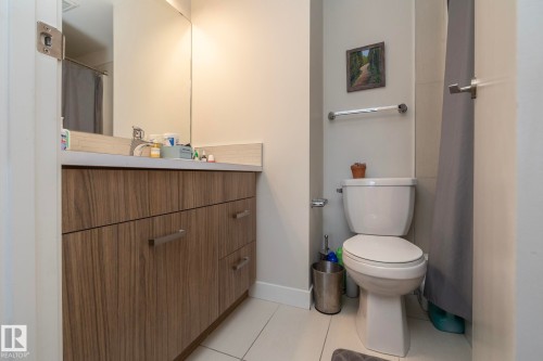 Bathroom vanity featuring wood-finish cabinetry, a solid surface countertop, and a large wall-mounted mirror - #2402 10410 102 Av Nw, Edmonton, AB - Indoor Photo Showing Bathroom