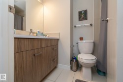 Bathroom vanity featuring wood-finish cabinetry, a solid surface countertop, and a large wall-mounted mirror - 