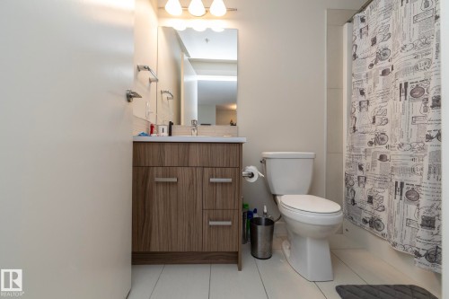 Bathroom featuring a wood-finish vanity with a white countertop, mirror, and overhead lighting - #2402 10410 102 Av Nw, Edmonton, AB - Indoor Photo Showing Bathroom
