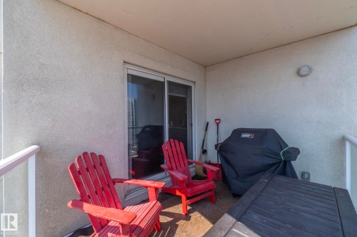 Balcony with textured stucco walls, sliding glass door, overhead lighting fixture, and a glass-paneled railing - #2402 10410 102 Av Nw, Edmonton, AB - Outdoor With Exterior