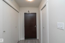 Entryway with light grey wood-finish flooring, a dark wood-finish door, and integrated overhead lighting - 