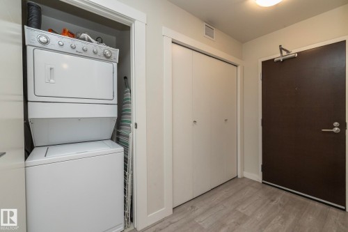 In-unit stacked washer and dryer with white finish and chrome controls, situated in a dedicated laundry closet - #2402 10410 102 Av Nw, Edmonton, AB - Indoor Photo Showing Laundry Room