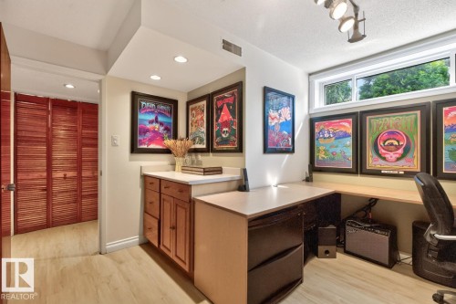 Dedicated workspace featuring a built-in desk, upper window, track lighting, light wood-finish flooring, and cabinetry with a light-colored countertop - 4631 113A Street Nw, Edmonton, AB - Indoor