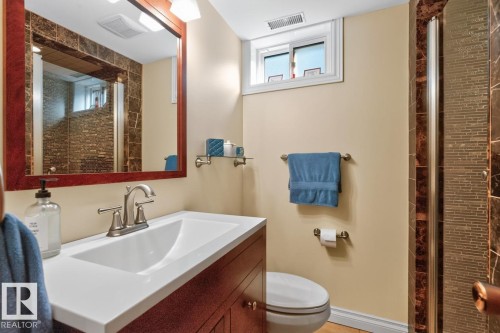 Bathroom featuring a dark wood vanity with white countertop, chrome faucet, and a framed mirror with integrated lighting - 4631 113A Street Nw, Edmonton, AB - Indoor Photo Showing Bathroom
