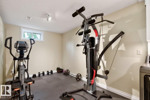Dedicated fitness space featuring neutral painted walls and a window for natural light; - 4631 113A Street Nw, Edmonton, AB - Indoor Photo Showing Gym Room