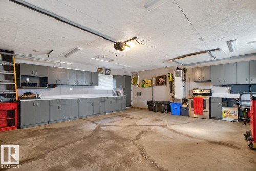 Spacious garage featuring extensive gray cabinetry, white countertops, fluorescent lighting fixtures, and a concrete floor - 4631 113A Street Nw, Edmonton, AB - Indoor Photo Showing Garage