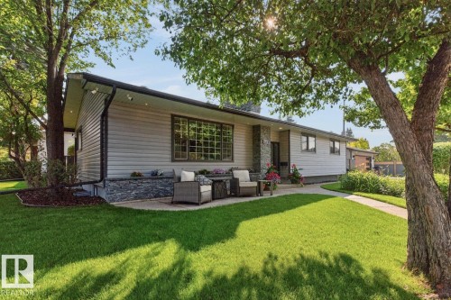 Ranch-style exterior featuring light-toned horizontal siding with stone veneer accents, a prominent front window with grid patterns, and a covered entry - 4631 113A Street Nw, Edmonton, AB - Outdoor