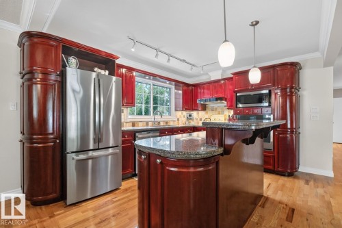 Kitchen featuring rich wood cabinetry, stainless steel appliances, and a central island with a granite countertop - 4631 113A Street Nw, Edmonton, AB - Indoor Photo Showing Kitchen