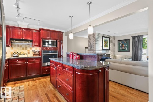Kitchen featuring cherry-stained cabinetry, stainless steel appliances, granite countertops, and a tile backsplash - 4631 113A Street Nw, Edmonton, AB - Indoor Photo Showing Kitchen