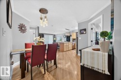 Dining area with wood-finish flooring featuring a glass-top table, crown molding, and a contemporary chandelier - 