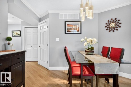 Dining area featuring light wood-finish flooring, crown molding, and a contemporary chandelier - #306 13111 140 Av Nw, Edmonton, AB - Indoor Photo Showing Dining Room