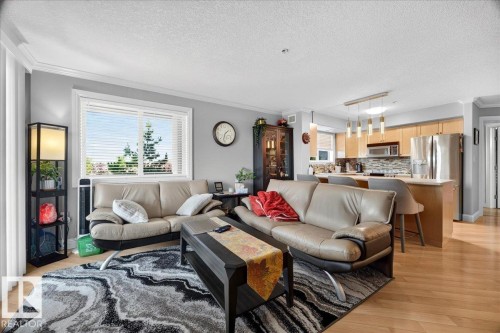 Open-concept living space featuring wood-finish flooring and crown molding - #306 13111 140 Av Nw, Edmonton, AB - Indoor Photo Showing Living Room
