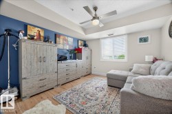Living space featuring wood-finish flooring, a ceiling fan with integrated lighting, and a window with horizontal blinds - 