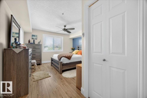 Bedroom featuring wood-finish flooring, a ceiling fan, and a window with horizontal blinds - #306 13111 140 Av Nw, Edmonton, AB - Indoor