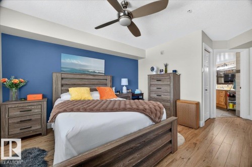 Bedroom with wood-finish flooring, a ceiling fan, and a blue accent wall - #306 13111 140 Av Nw, Edmonton, AB - Indoor Photo Showing Bedroom