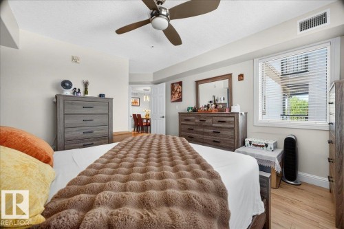 Bedroom featuring wood-finish flooring, a ceiling fan, a window with blinds, and white trim - #306 13111 140 Av Nw, Edmonton, AB - Indoor Photo Showing Bedroom