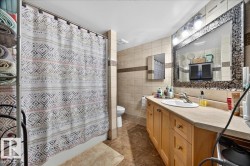 Bathroom featuring a light wood-finish vanity with a single basin sink and a large framed mirror with mosaic-style accents - 