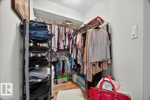Walk-in closet featuring wire shelving, hanging rods, and wood-finish flooring - #306 13111 140 Av Nw, Edmonton, AB - Indoor With Storage