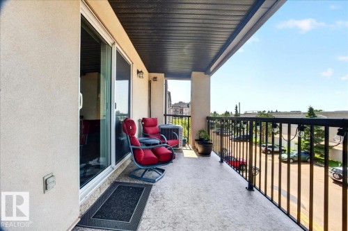 Outdoor balcony featuring a textured concrete floor, black metal railings, and a dark soffit - #306 13111 140 Av Nw, Edmonton, AB - Outdoor With Balcony With Exterior