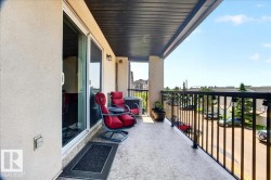 Outdoor balcony featuring a textured concrete floor, black metal railings, and a dark soffit - 