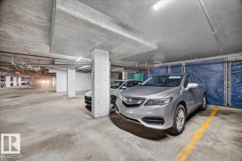 Underground parking space featuring concrete flooring, structural columns, and overhead lighting - #306 13111 140 Av Nw, Edmonton, AB - Indoor Photo Showing Garage
