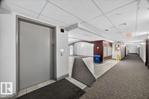 Central elevator access with call buttons features a textured gray door - #306 13111 140 Av Nw, Edmonton, AB - Indoor Photo Showing Other Room