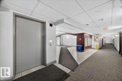 Central elevator access with call buttons features a textured gray door - 