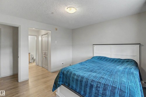 Bedroom featuring wood-finish flooring, light gray wall tones, and a ceiling-mounted light fixture - #204 309 Clareview Station Dr Nw, Edmonton, AB - Indoor Photo Showing Bedroom