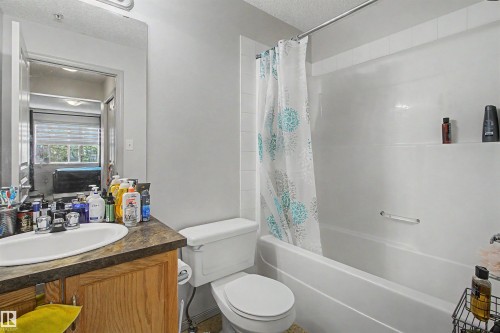 Bathroom featuring a vanity with a wood-finish cabinet, a drop-in sink, and a dark laminate countertop - #204 309 Clareview Station Dr Nw, Edmonton, AB - Indoor Photo Showing Bathroom