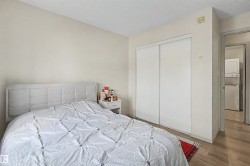 Bedroom featuring light wood-finish flooring, light-toned walls, and a built-in closet with sliding white doors - 