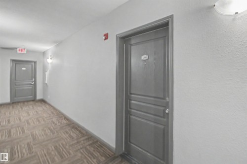 Hallway featuring wood-finish flooring, light grey walls, and semi-flush wall sconces - #204 309 Clareview Station Dr Nw, Edmonton, AB - Indoor Photo Showing Other Room