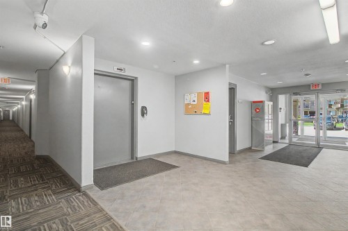 Building entry features double glass doors, light gray tiled flooring, and recessed ceiling lighting - #204 309 Clareview Station Dr Nw, Edmonton, AB - Indoor Photo Showing Other Room