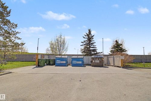 Paved lot with perimeter fencing and mature trees - #204 309 Clareview Station Dr Nw, Edmonton, AB - Outdoor
