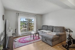 Living area featuring wood-finish flooring, a large window, and a balcony with a wrought iron railing - 
