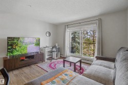 Spacious living area featuring light wood-finish flooring, white walls, and a sliding glass door leading to a private balcony - 