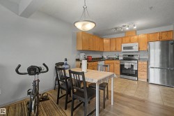 Kitchen and dining area featuring wood-finish flooring, light wood cabinetry, stainless steel appliances, and a track lighting fixture - 