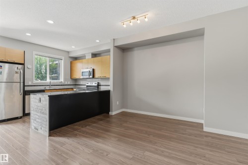 Open-concept living area featuring wood-finish flooring - #62 675 Watt Bv Sw, Edmonton, AB - Indoor Photo Showing Kitchen