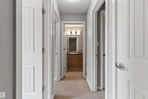 Carpeted hallway with light gray walls, white paneled doors, and brushed nickel hardware - #62 675 Watt Bv Sw, Edmonton, AB - Indoor Photo Showing Other Room